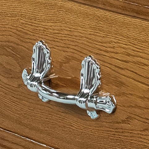 Chrome bar handle on ornate scroll brackets, mounted on the oak veneered side of The Bolsover