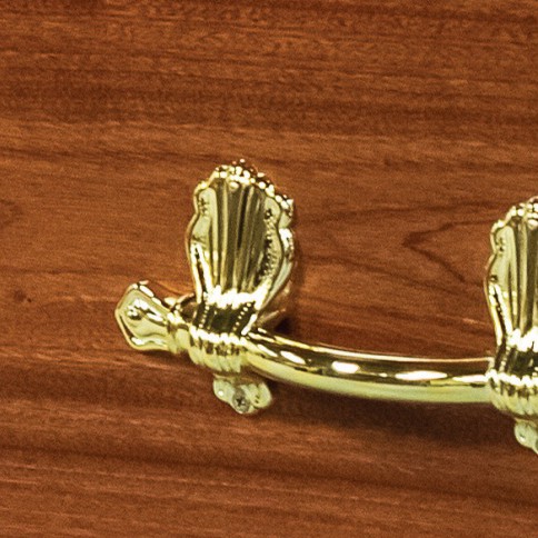 Polished brass bar handle on ornate scroll brackets, mounted on the mahogany veneered side of The Milldale
